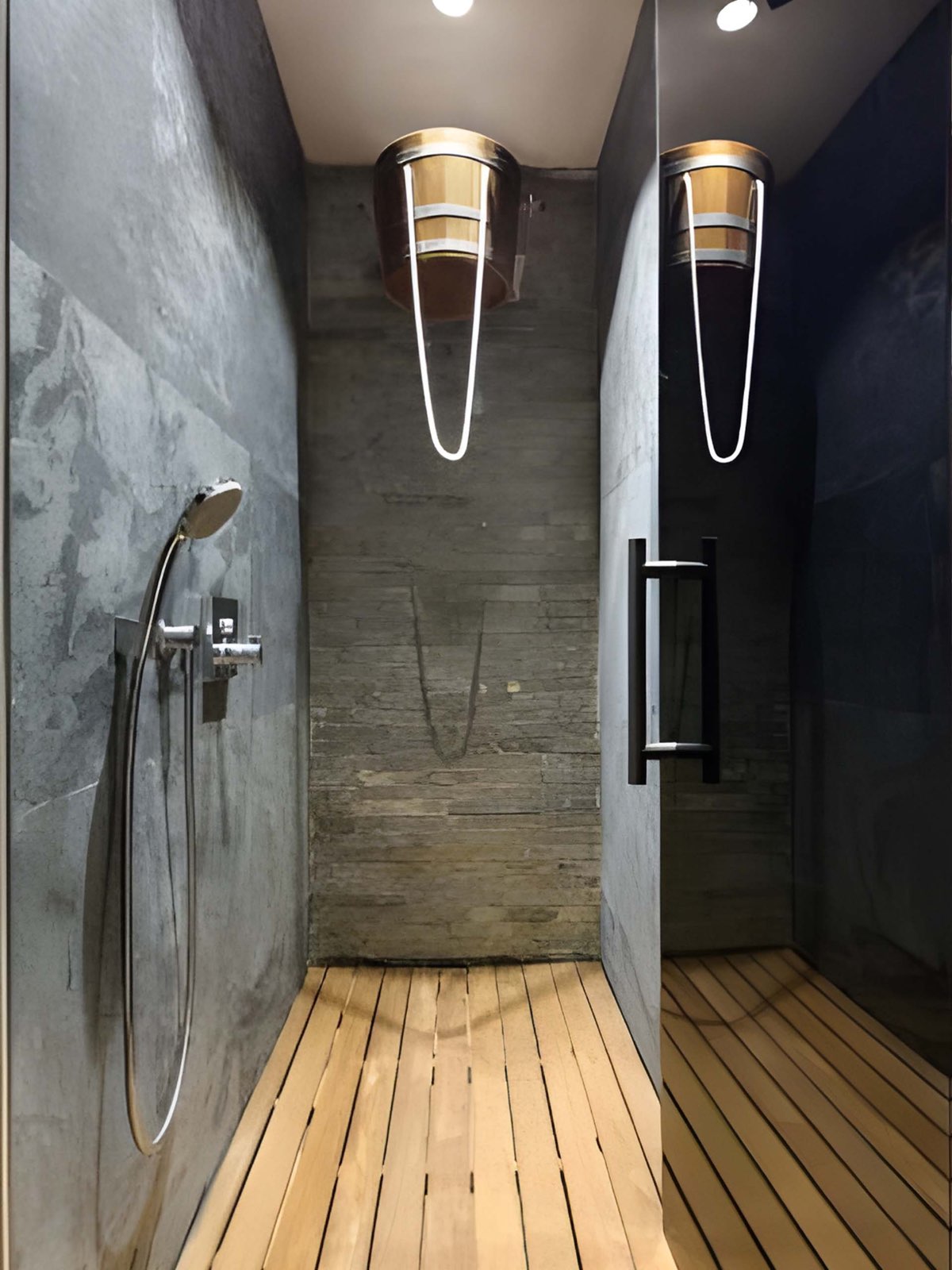 Narrow shower alley with grey stone walls, a split-face stone back wall, a hand shower on a wall valve, two ceiling-mounted timber shock buckets and a light timber slatted floor with open joints